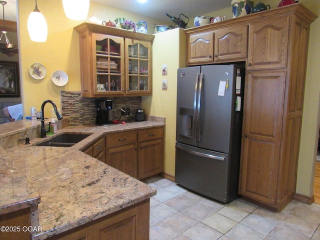 kitchen with decorative light fixtures, sink, stainless steel fridge, backsplash, and kitchen peninsula