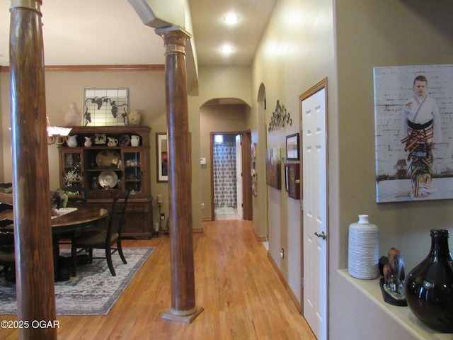 hallway featuring light hardwood / wood-style floors and ornate columns