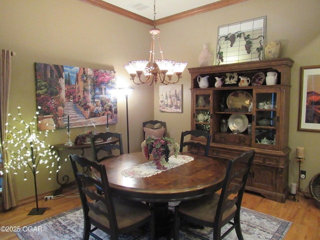 dining room featuring ornamental molding, a chandelier, and light hardwood / wood-style flooring