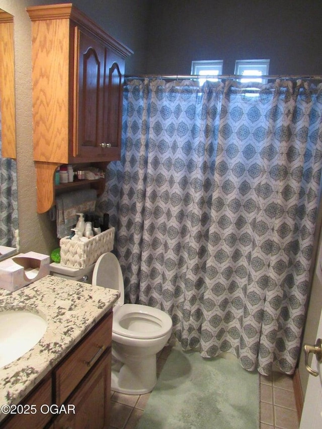 bathroom featuring walk in shower, vanity, toilet, and tile patterned flooring