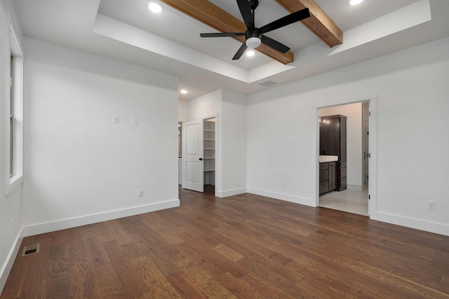 empty room with a tray ceiling, beam ceiling, dark hardwood / wood-style floors, and ceiling fan