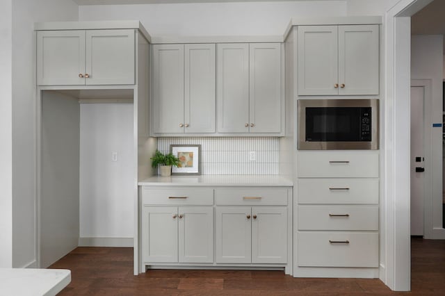 kitchen with built in microwave, white cabinetry, tasteful backsplash, and dark hardwood / wood-style flooring