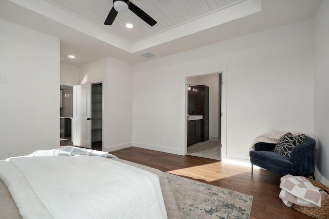 bedroom with ceiling fan, connected bathroom, a tray ceiling, dark hardwood / wood-style flooring, and wooden ceiling