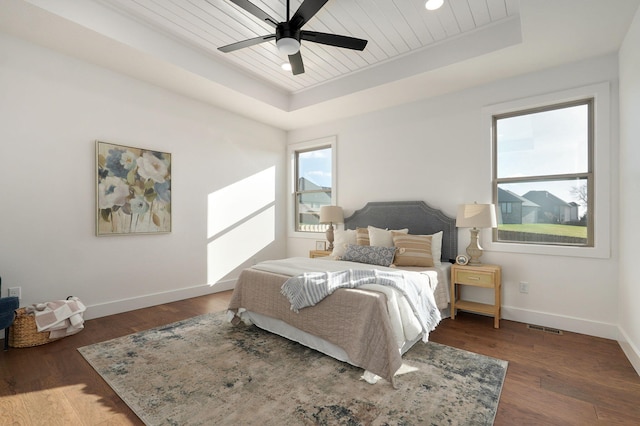 bedroom featuring ceiling fan, a tray ceiling, dark hardwood / wood-style flooring, and wooden ceiling