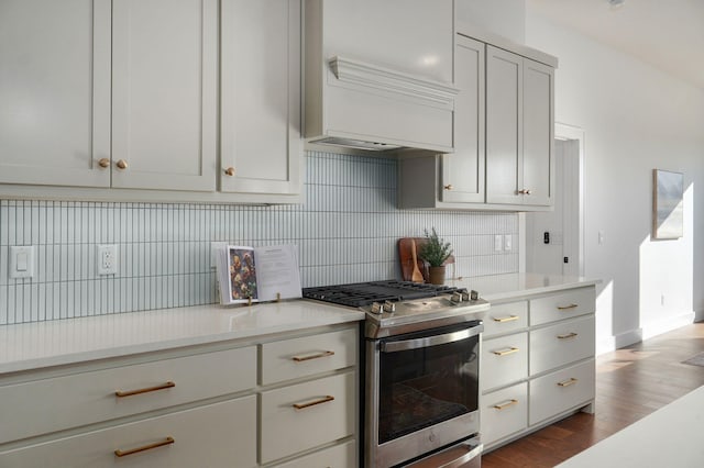 kitchen featuring tasteful backsplash, hardwood / wood-style floors, stainless steel gas range oven, and custom range hood