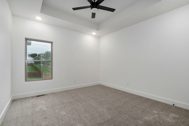 spare room featuring carpet floors, ceiling fan, and a tray ceiling