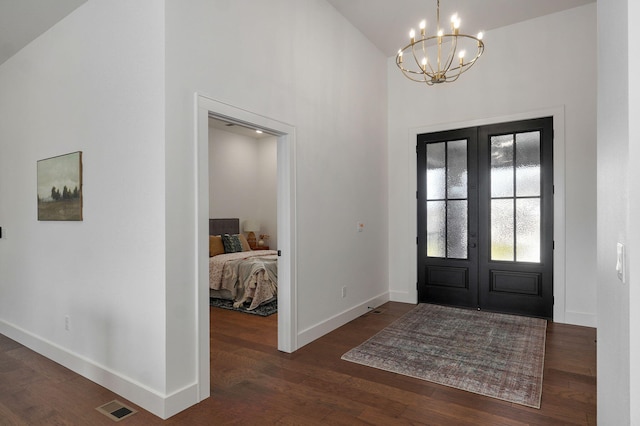 foyer entrance with french doors, dark hardwood / wood-style floors, an inviting chandelier, and a high ceiling