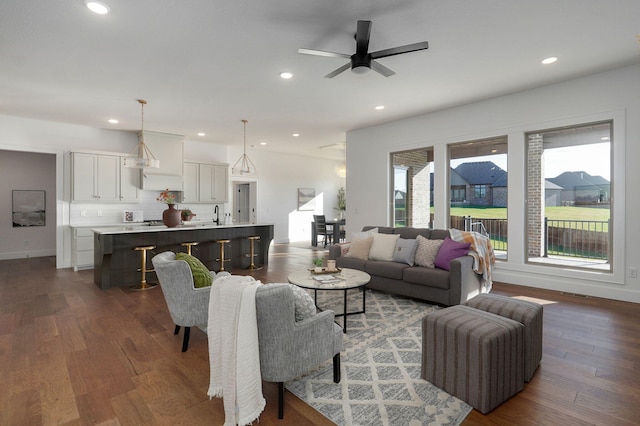 living room featuring ceiling fan, dark hardwood / wood-style floors, and sink