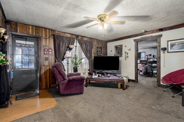 living room with ceiling fan, a wealth of natural light, a textured ceiling, and wooden walls