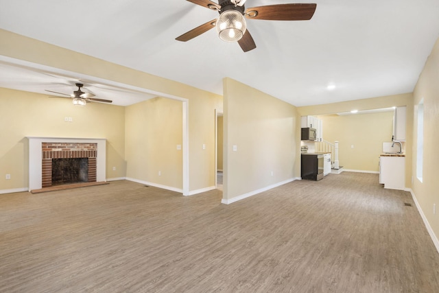 unfurnished living room featuring ceiling fan, a fireplace, and wood-type flooring