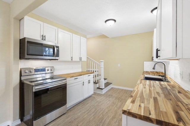 kitchen with white cabinetry, appliances with stainless steel finishes, sink, and wooden counters