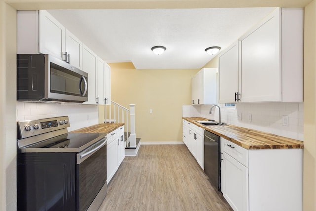 kitchen with wood counters, sink, white cabinets, and appliances with stainless steel finishes