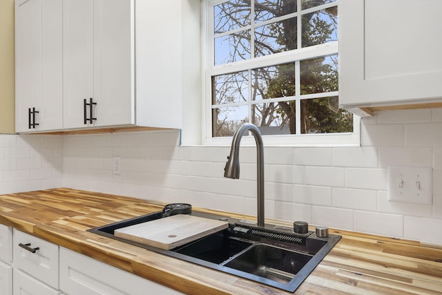 kitchen featuring white cabinetry, sink, decorative backsplash, and wooden counters