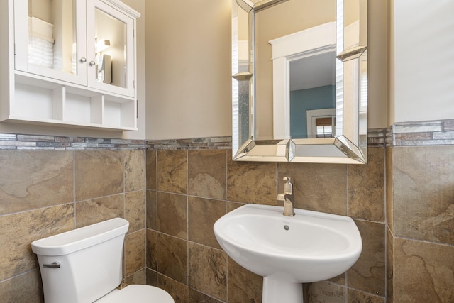 bathroom featuring sink, tile walls, and toilet