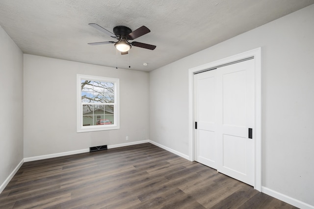 unfurnished bedroom with a closet, dark hardwood / wood-style floors, a textured ceiling, and ceiling fan