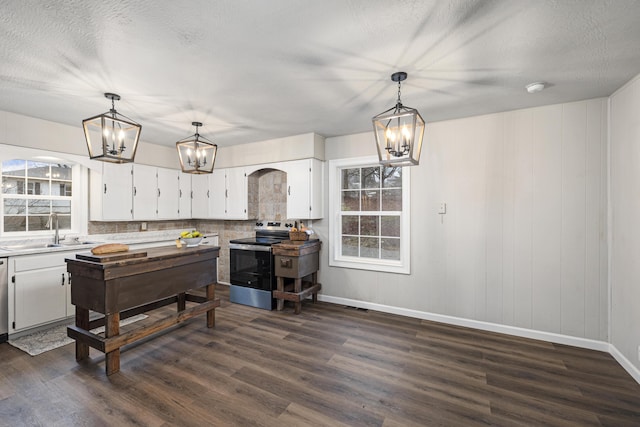 kitchen featuring sink, decorative light fixtures, stainless steel electric stove, and white cabinets