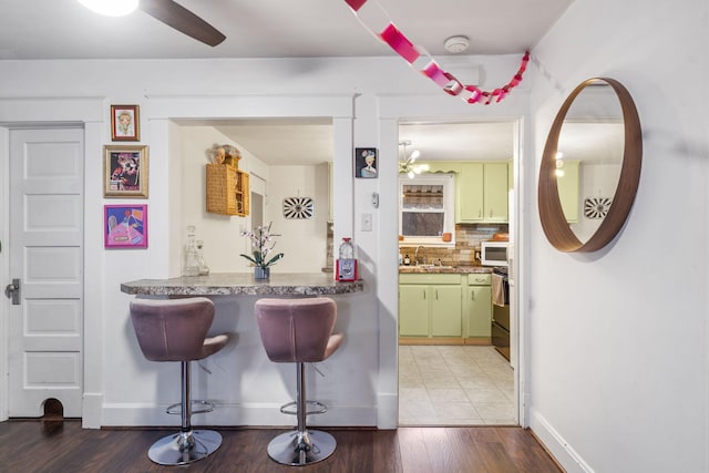 kitchen featuring sink, stove, backsplash, hardwood / wood-style floors, and green cabinetry