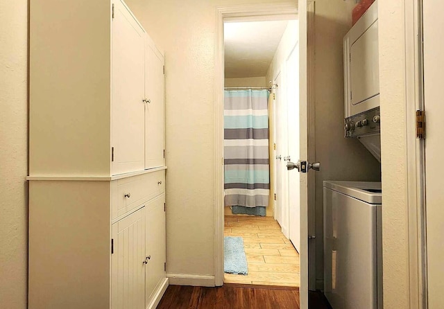 laundry room with hardwood / wood-style flooring and stacked washer / drying machine