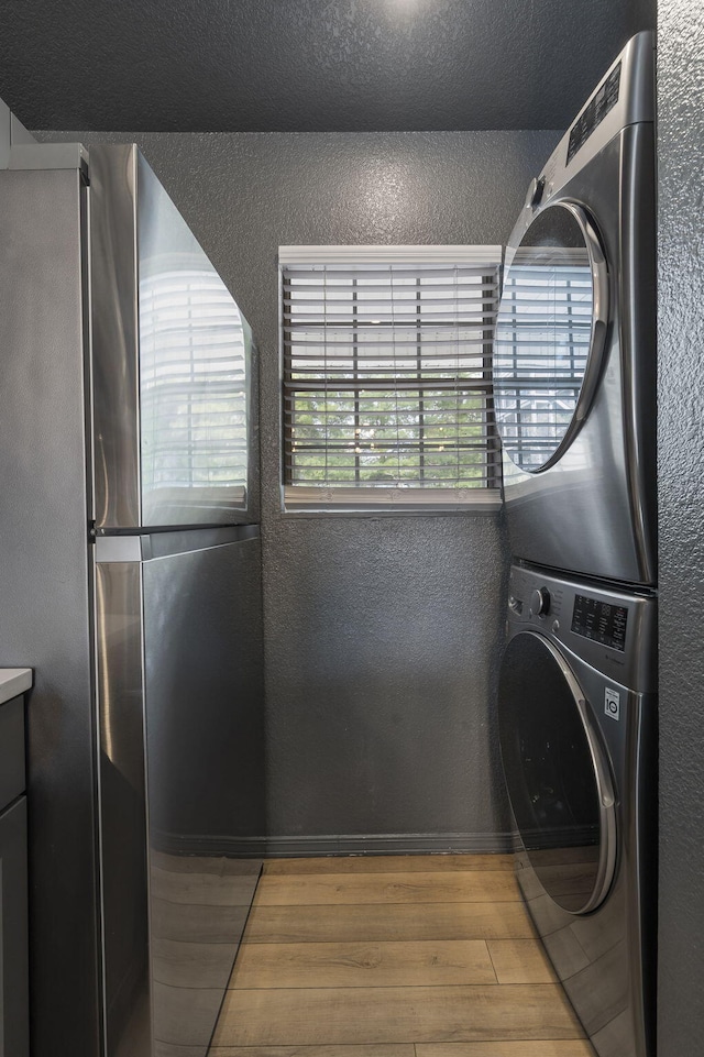 laundry room featuring stacked washer and dryer and hardwood / wood-style floors