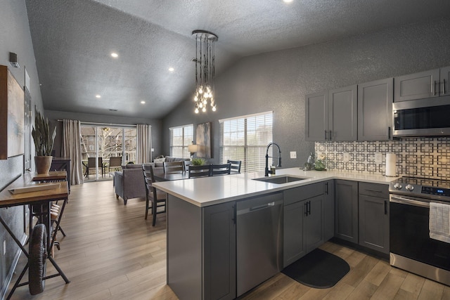 kitchen featuring gray cabinetry, sink, stainless steel appliances, and kitchen peninsula