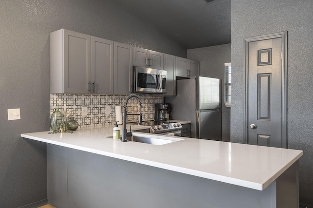 kitchen featuring stainless steel appliances, gray cabinets, and kitchen peninsula