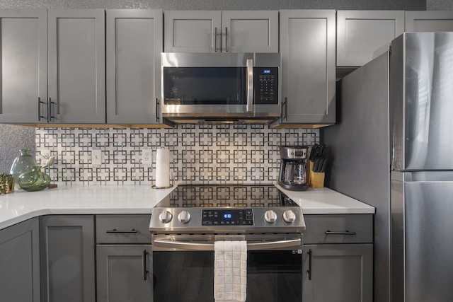 kitchen featuring tasteful backsplash, gray cabinets, and stainless steel appliances