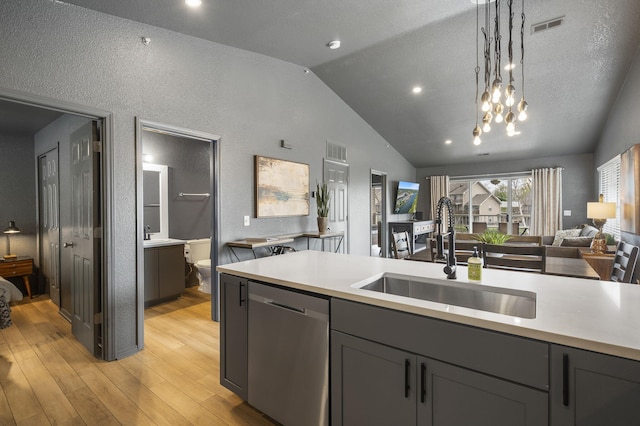 kitchen with sink, vaulted ceiling, hanging light fixtures, light hardwood / wood-style flooring, and stainless steel dishwasher