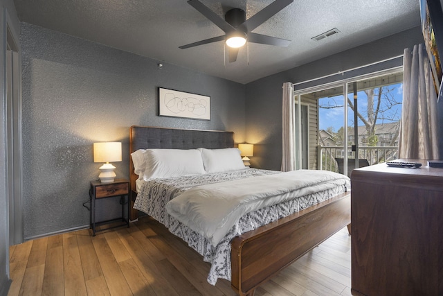 bedroom featuring ceiling fan, hardwood / wood-style flooring, access to outside, and a textured ceiling