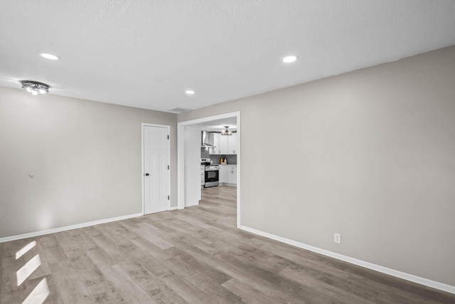 spare room with recessed lighting, baseboards, and wood finished floors