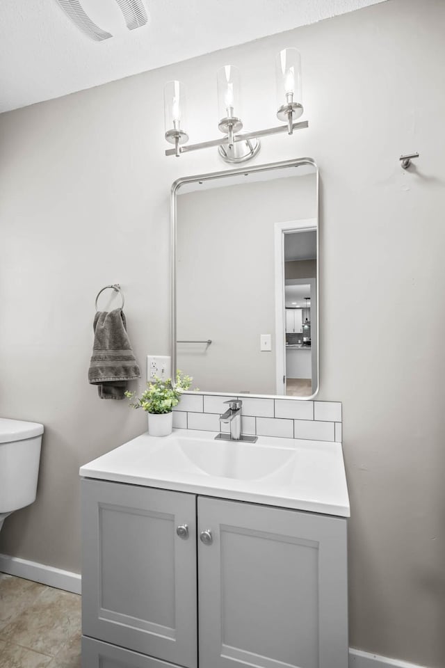 half bathroom featuring vanity, toilet, baseboards, and visible vents