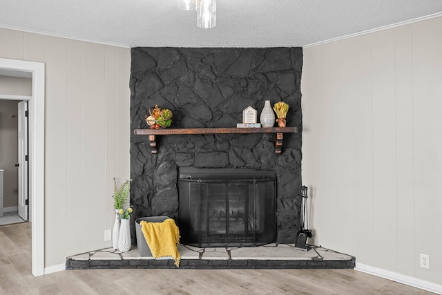 details featuring a stone fireplace, ornamental molding, a textured ceiling, and wood finished floors