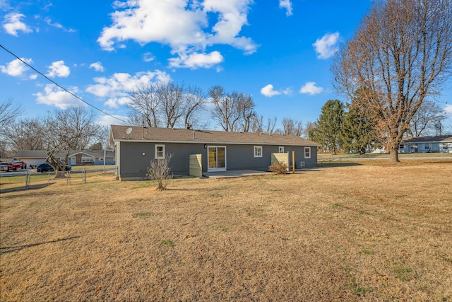 rear view of property featuring a patio area, a yard, and fence