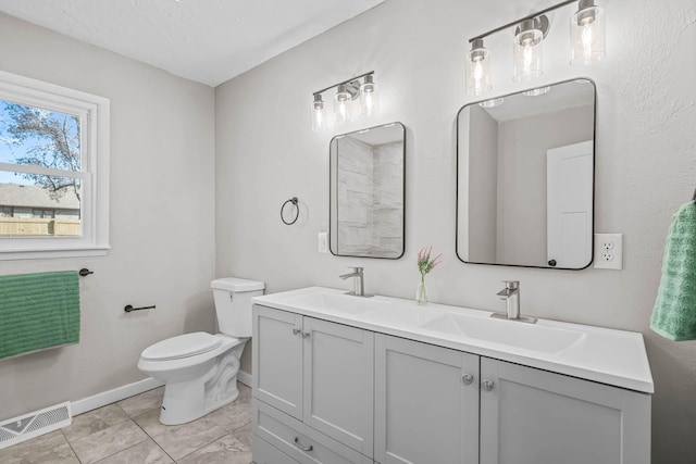 bathroom with double vanity, visible vents, toilet, and a sink