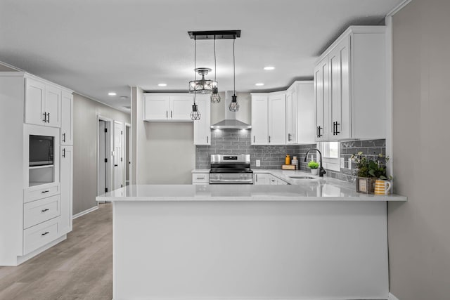 kitchen with wall chimney range hood, stainless steel electric range, white cabinets, and a sink