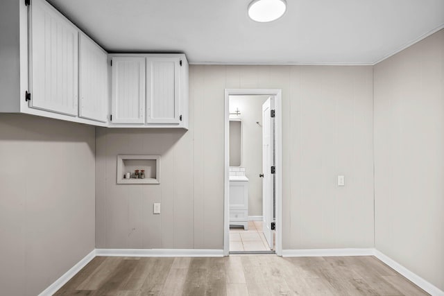 laundry room featuring cabinet space, hookup for a washing machine, light wood-type flooring, and baseboards