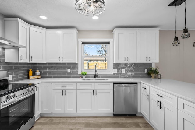 kitchen with a sink, stainless steel appliances, light countertops, white cabinetry, and light wood-type flooring