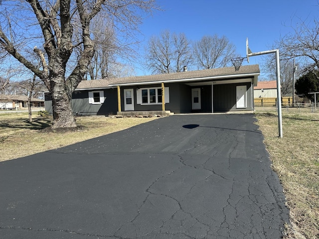 ranch-style home with an attached carport, aphalt driveway, and fence