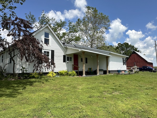 back of house featuring a lawn and a barn