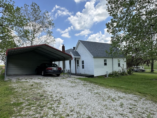 view of home's exterior with gravel driveway, roof with shingles, a detached carport, a yard, and a chimney
