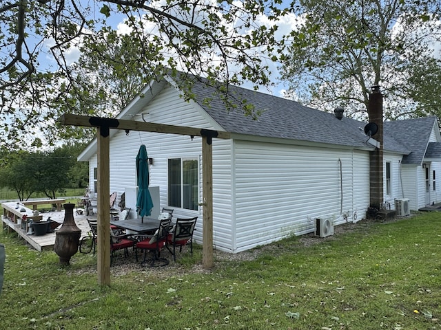 view of property exterior with a shingled roof, a lawn, central AC, and a chimney