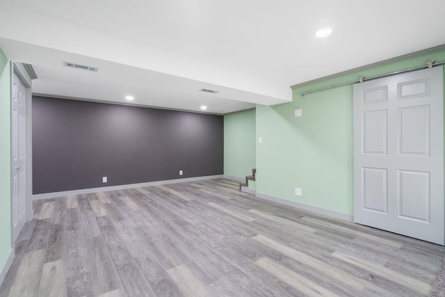 basement featuring light hardwood / wood-style flooring and a barn door