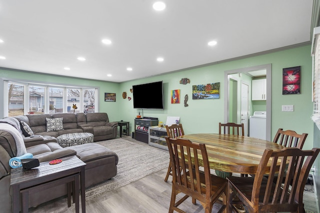 living room with ornamental molding, washer / dryer, and light hardwood / wood-style floors