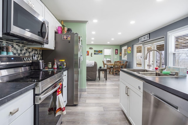 kitchen featuring sink, white cabinets, light hardwood / wood-style floors, stainless steel appliances, and french doors