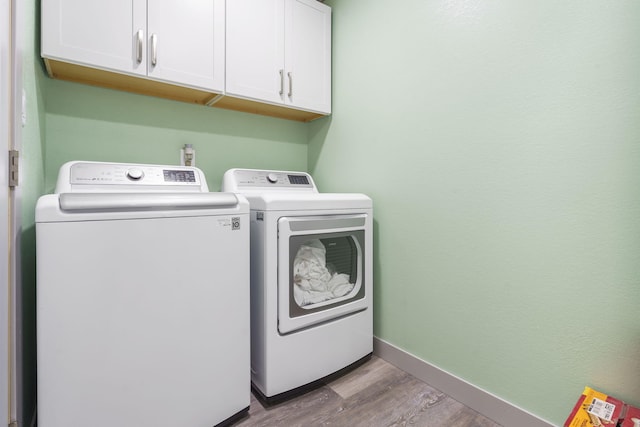 laundry area with cabinets, independent washer and dryer, and light hardwood / wood-style floors