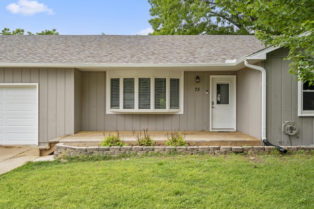 view of exterior entry with a garage and a lawn