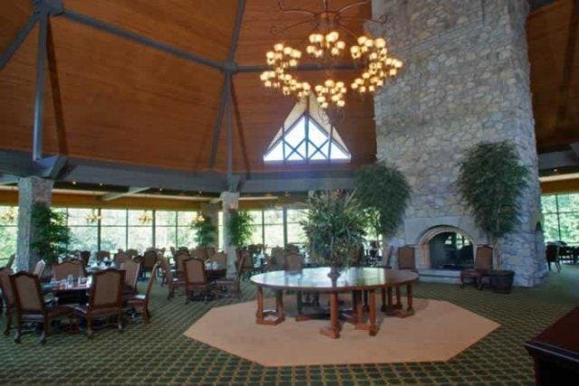 carpeted dining area featuring a wealth of natural light, a high ceiling, and a notable chandelier