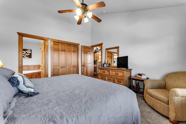 carpeted bedroom with a closet, a towering ceiling, ceiling fan, and ensuite bath