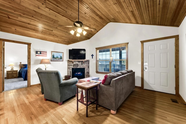 living room featuring vaulted ceiling, wood-type flooring, wood ceiling, and a stone fireplace