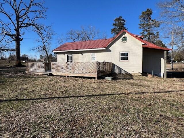 rear view of house with a wooden deck and a lawn