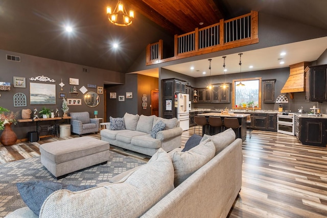 living room with high vaulted ceiling, sink, a chandelier, and light wood-type flooring